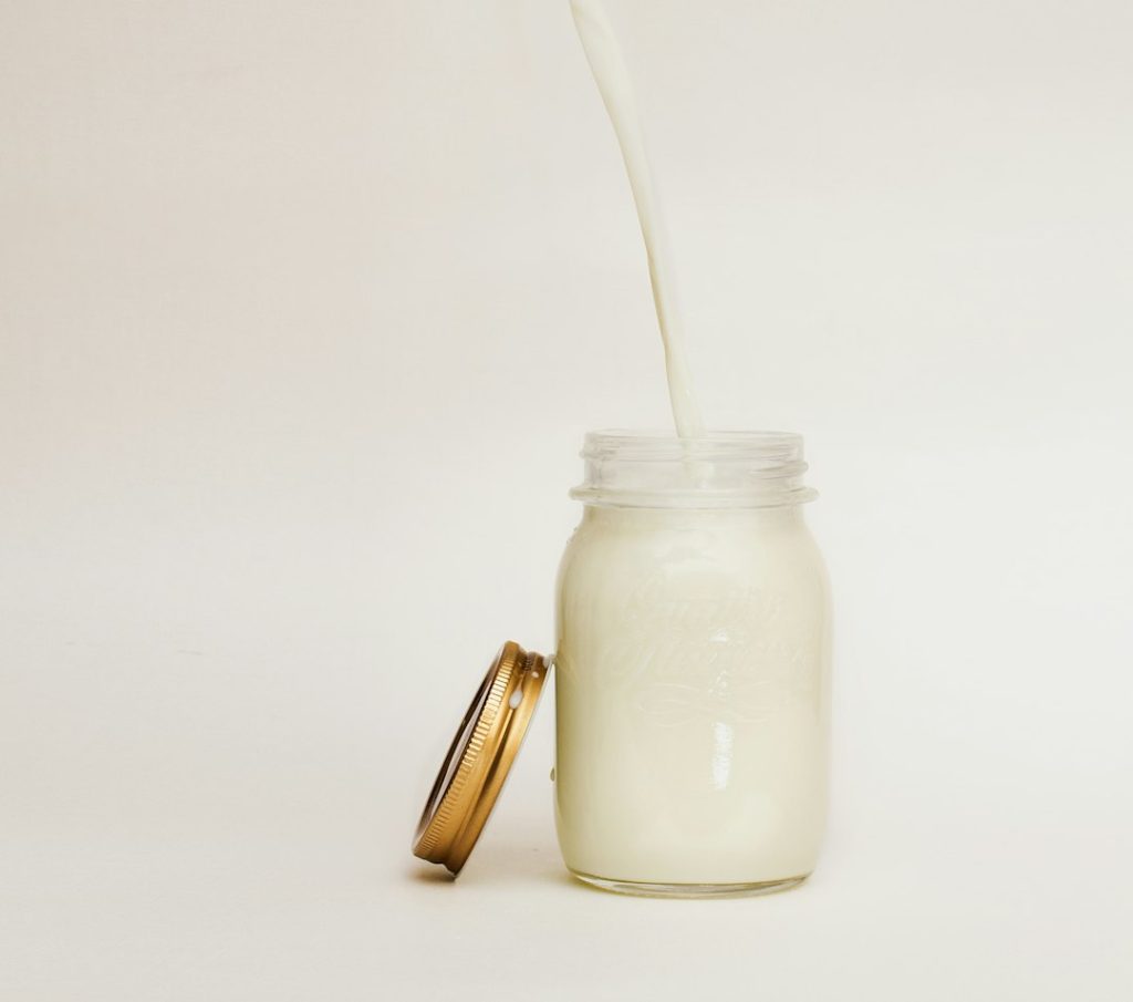 Milk poured into a glass jar, an ingredient for a heavy cream substitute for cooking