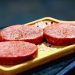 Three raw ground beef patties on a tray before cooking