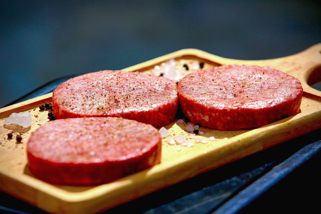Three raw ground beef patties on a tray before cooking