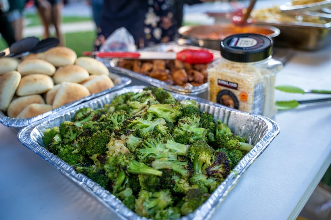 Cooked broccoli florets in a foil tray on an outdoor table