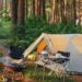 Camping setup with tent and cooking gear in a forest for outdoor pancake making.
