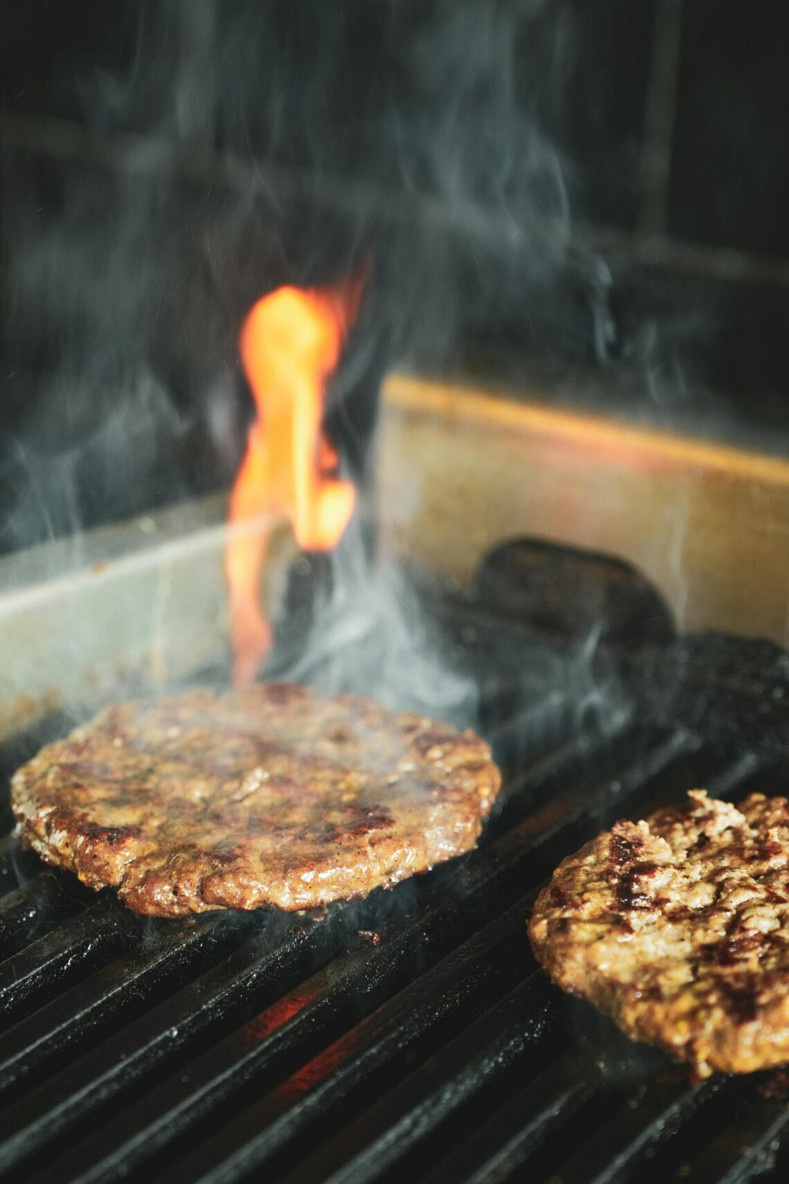 Beef burger patties cooking on an outdoor grill