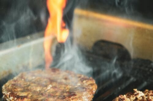 Beef burger patties cooking on an outdoor grill