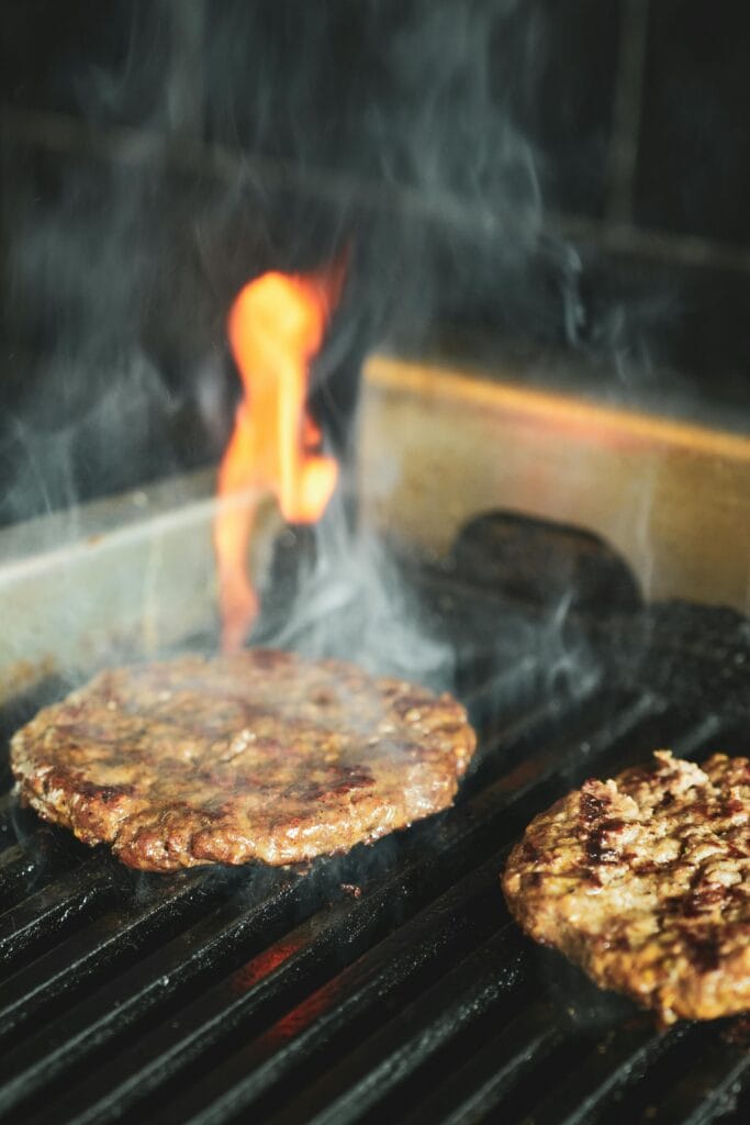 Beef burger patties cooking on a grill