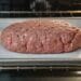 Raw meatloaf shaped on a lined rimmed baking sheet