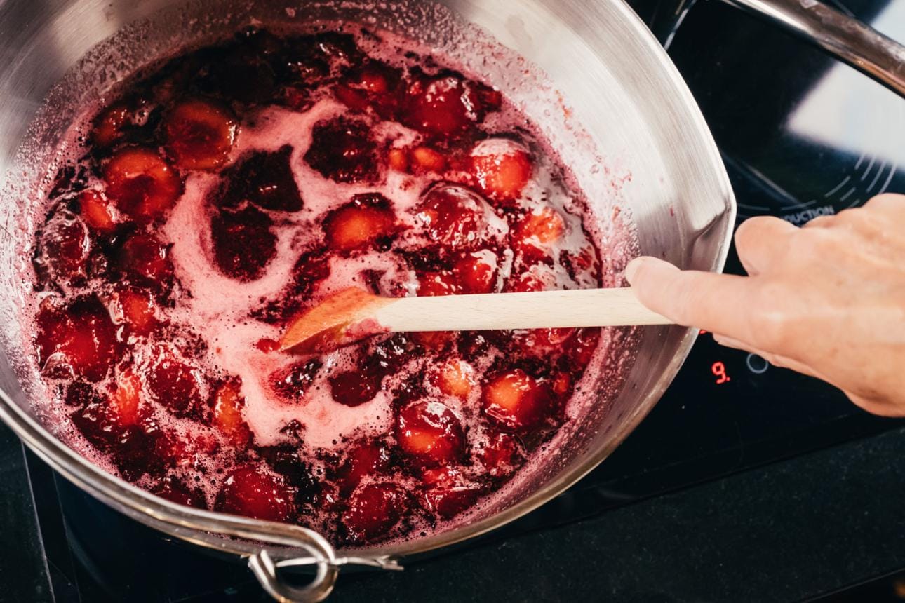 Red fruit simmering in a saucepan for homemade jelly preparation
