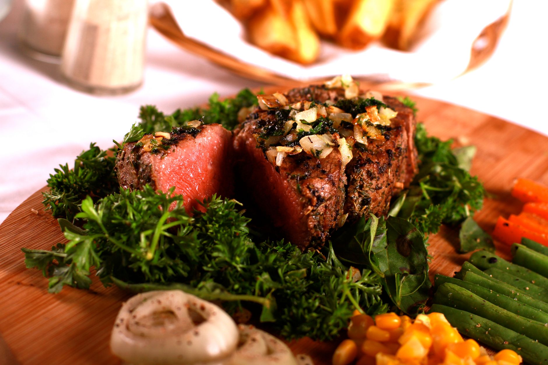 Sliced steak served with vegetables and a herb topping