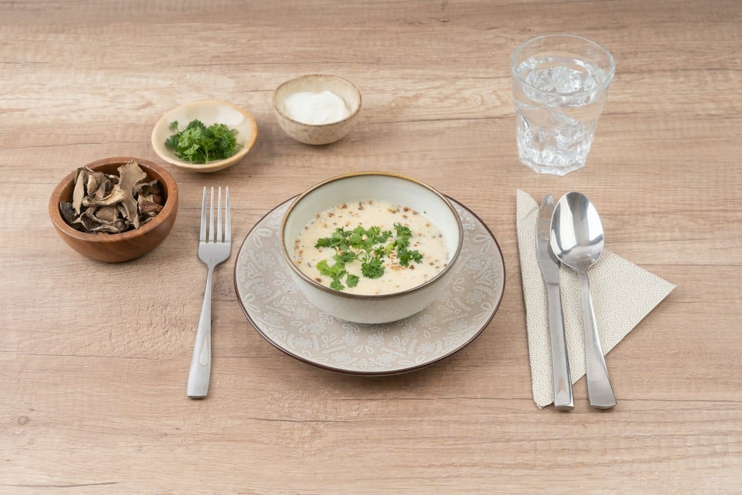 Mushroom soup on a table with bread and garnishes