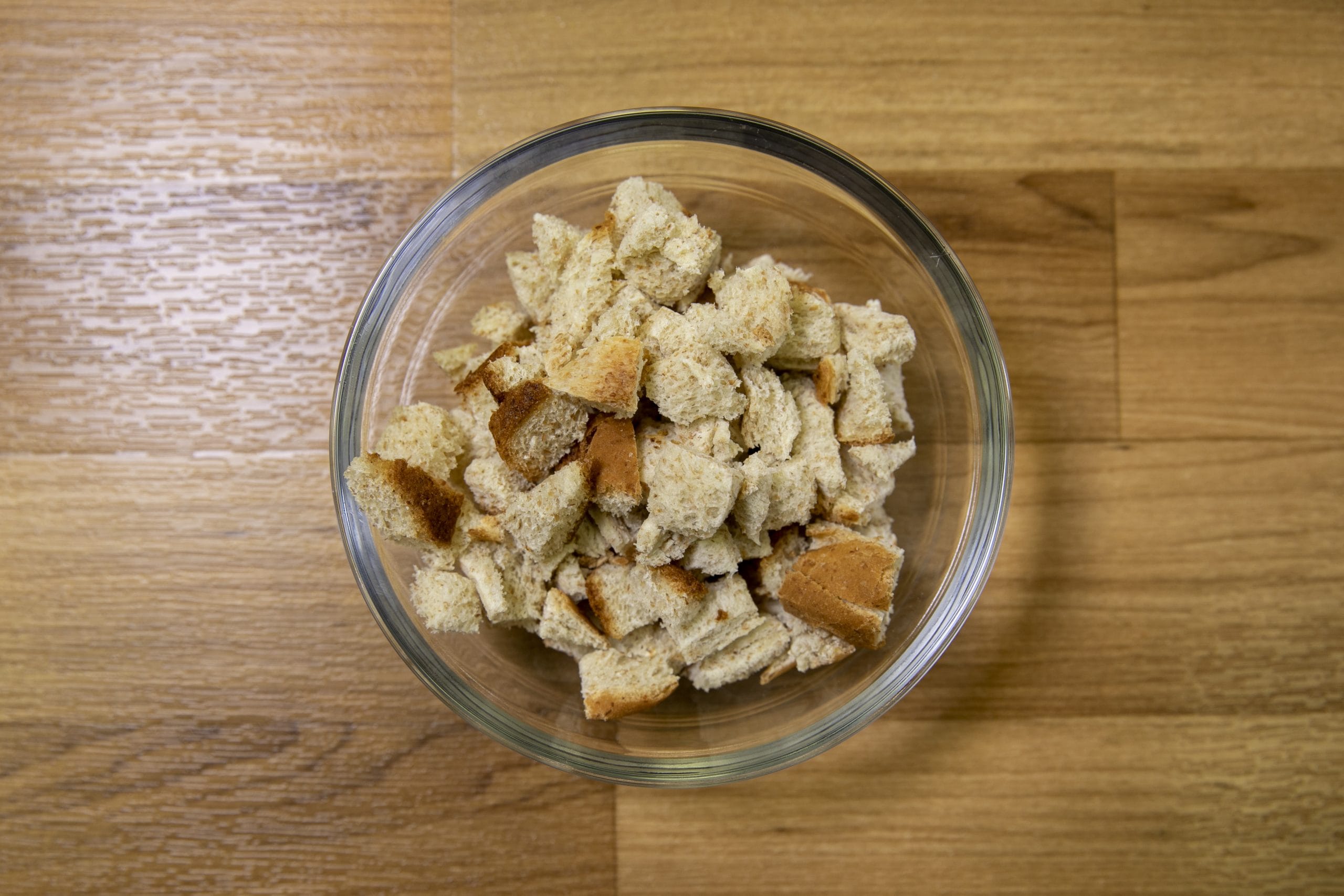 Dried bread pieces in a glass bowl before grinding into breadcrumbs