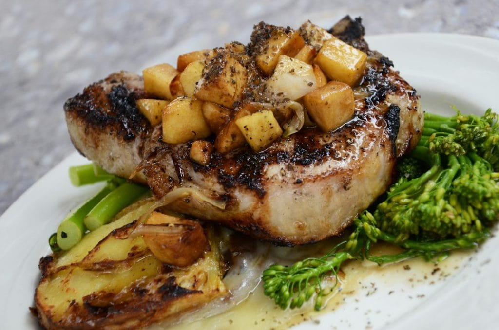 Pork chop topped with apples and served with vegetables