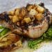 Pork chop topped with diced fruit beside green vegetables, serving inspiration