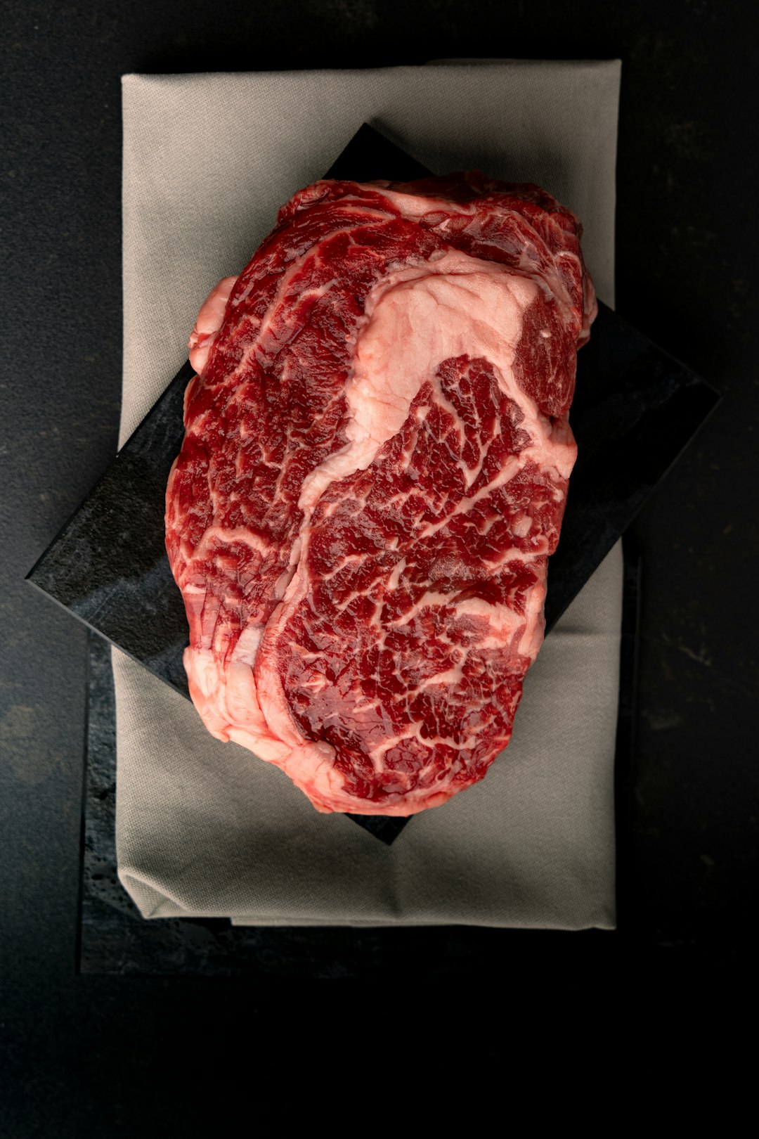Raw marbled ribeye steak on butcher paper