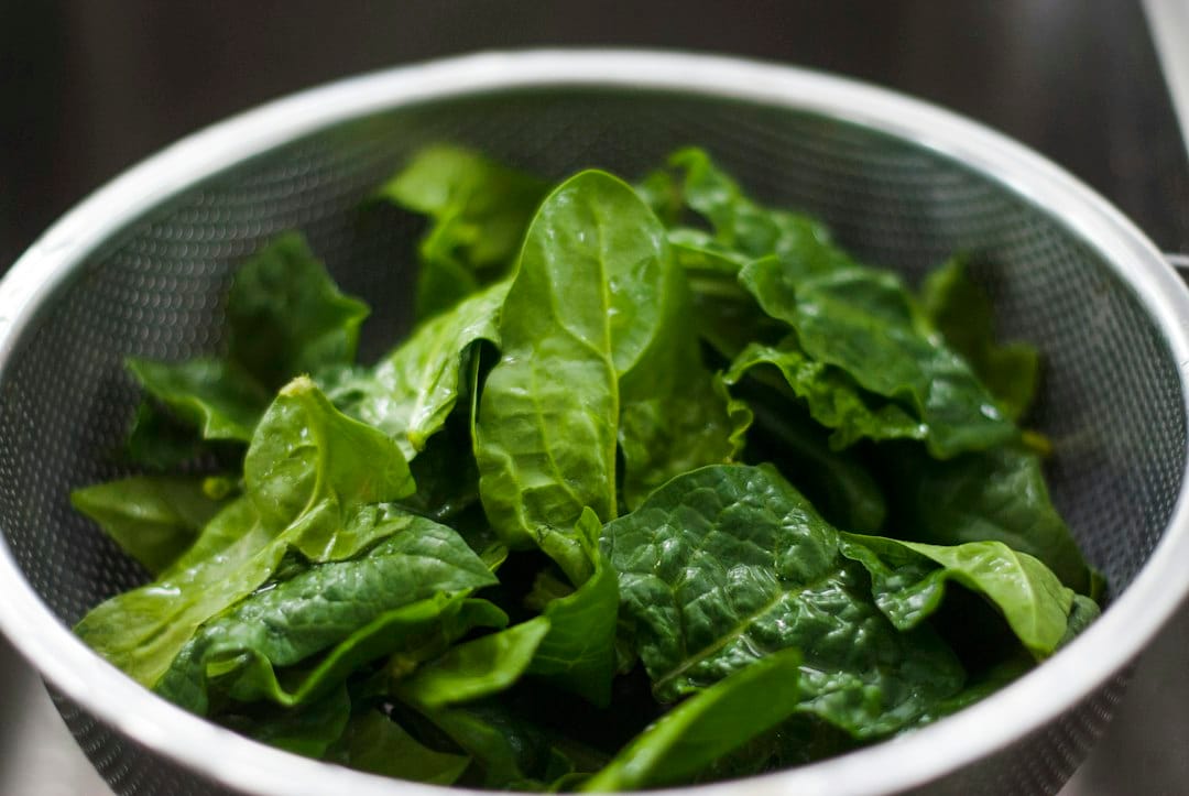 Fresh spinach leaves in a metal colander