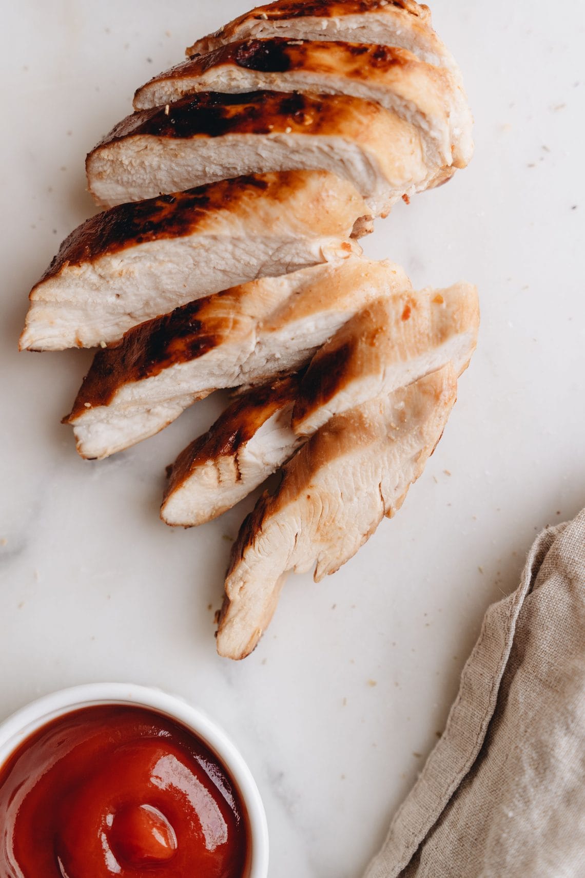 Sliced browned chicken breast on a white plate