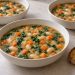 Carrot white bean soup with frozen spinach without cream in three bowls with whole beans and small carrot pieces.