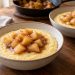 Stovetop apple cornmeal porridge for two served in two bowls with warm cinnamon apple cubes.