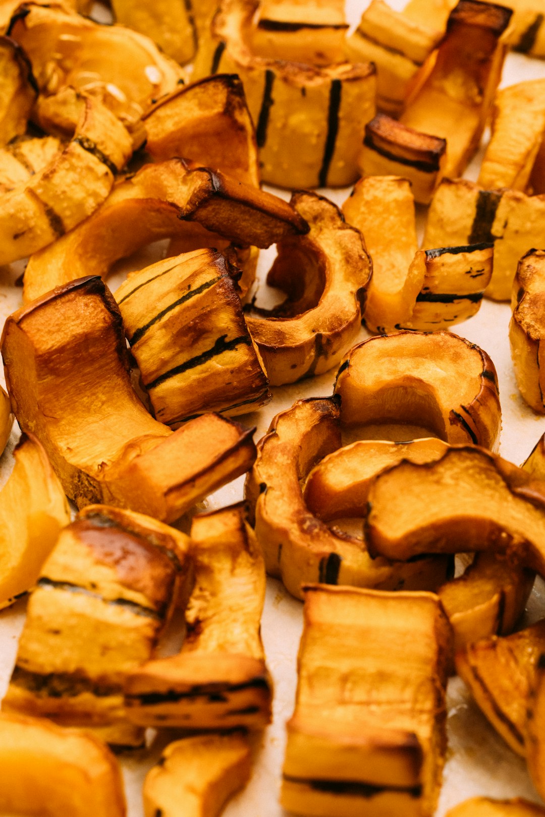 Roasted delicata squash half-moons with browned cut faces and edible striped skin