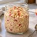 Thick overnight oats with small apple pieces and cinnamon in a wide-mouth glass jar.