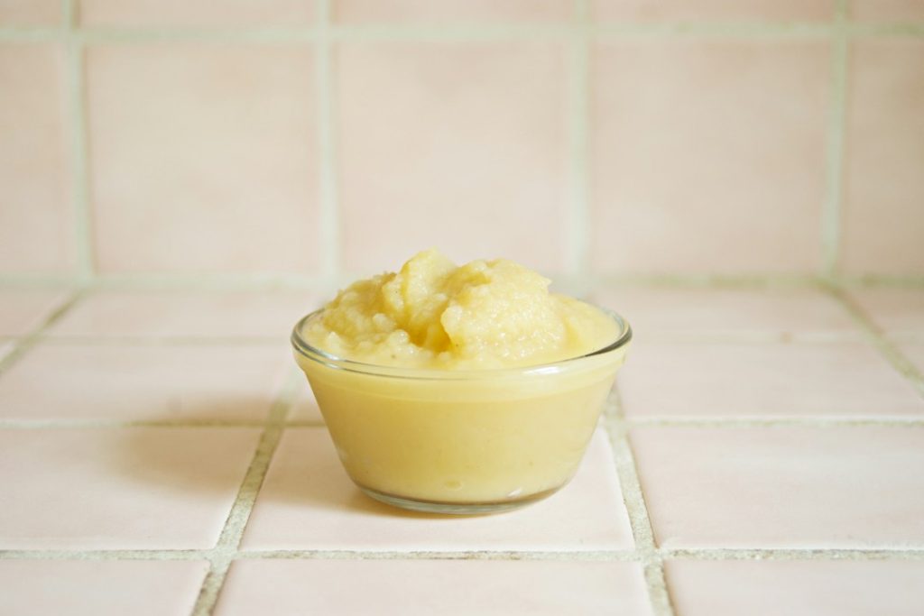 Applesauce in a bowl, with small pieces of apple visible.