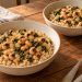 Two bowls of brown rice topped with black-eyed peas, chopped cooked collards, and softened onion.