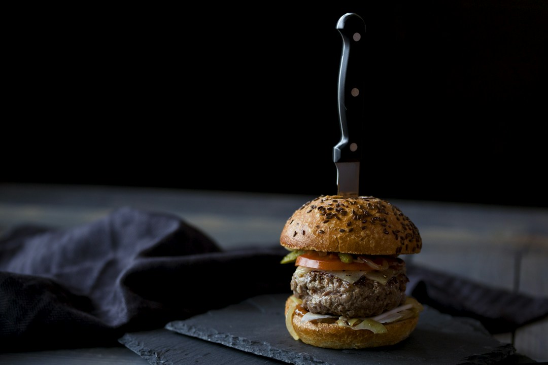 Burger in a seeded bun with tomato and onion, shown as a serving idea