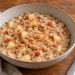 A bowl of creamy rolled oats with small cooked apple pieces, cinnamon, and a modest peanut butter swirl.