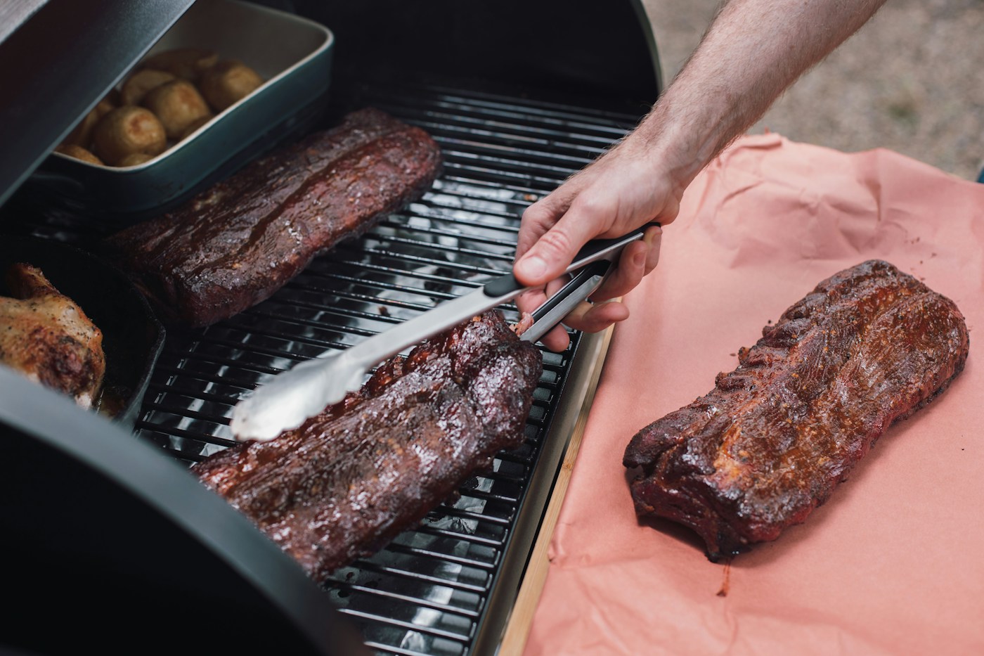 How to know when ribs are done: cooked pork rib racks being moved from a grill with tongs