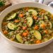 Lemon lentil zucchini soup with whole brown lentils, zucchini slices and diced carrot in a light broth.