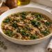 Lemony lentil and mushroom soup with kale in a bowl beside a lemon wedge