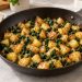 Potato and spinach breakfast hash without eggs, with golden potato cubes and finely chopped spinach in a skillet.