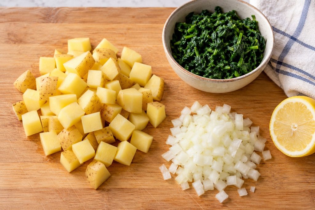 Even Yukon Gold potato cubes, diced onion and well-drained chopped spinach prepared for breakfast hash.