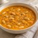 Pumpkin white bean soup with whole white beans and fine sage flecks in an orange pumpkin broth.