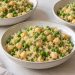 Three lunch bowls of fluffy white quinoa, green peas, whole chickpeas, and chopped dill.