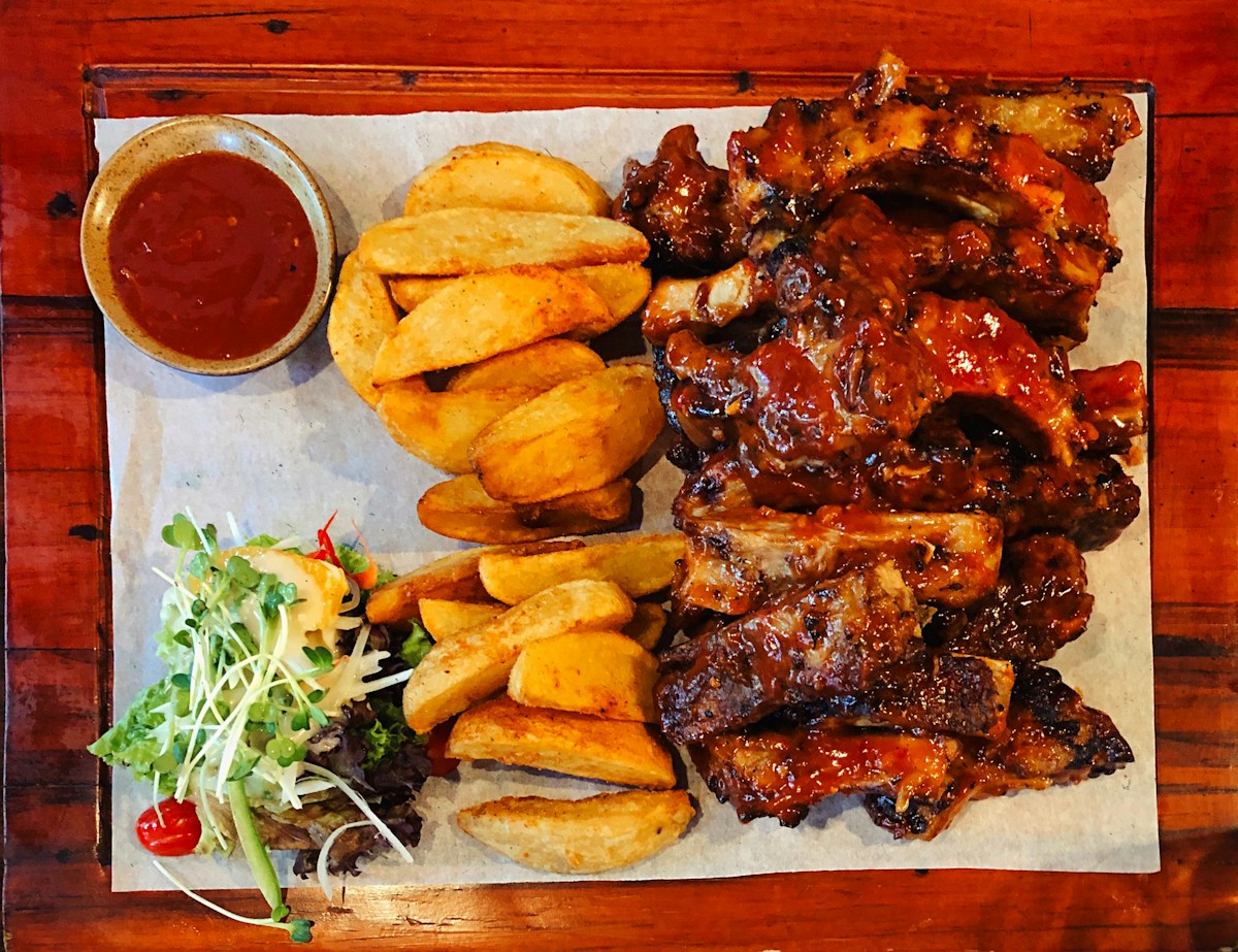 Sauced ribs served with potato wedges and salad