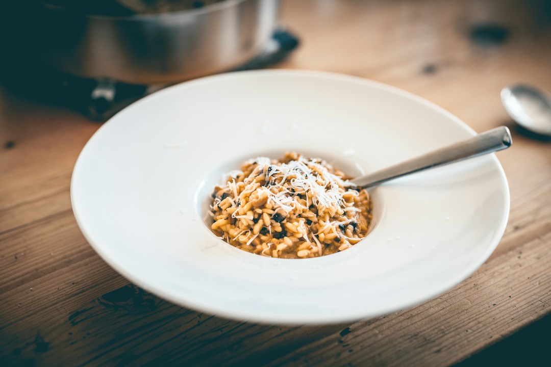 Mushroom risotto topped with grated cheese in a wide white bowl