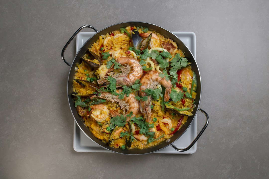 Seafood paella with shrimp, mussels and yellow rice in a wide shallow pan