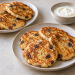 Rosemary raisin cottage cheese pancakes on two plates with plain yogurt alongside