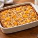 A small rectangular dish of baked oatmeal with soft peach pieces, visible oat flakes, and lightly golden edges.