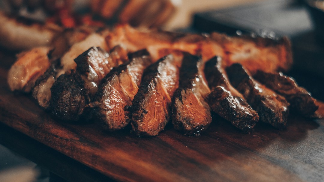 Browned steak slices on a wooden board accompanying the steak doneness temperature chart