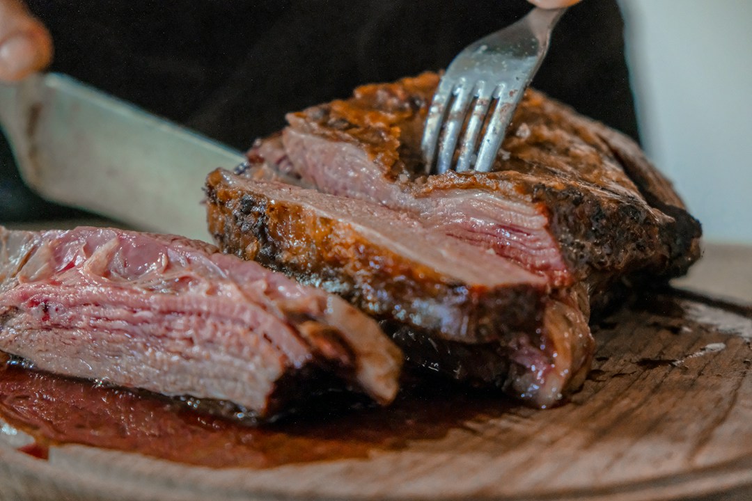 Cooked beef being carved on a board for the steak doneness temperature chart guide
