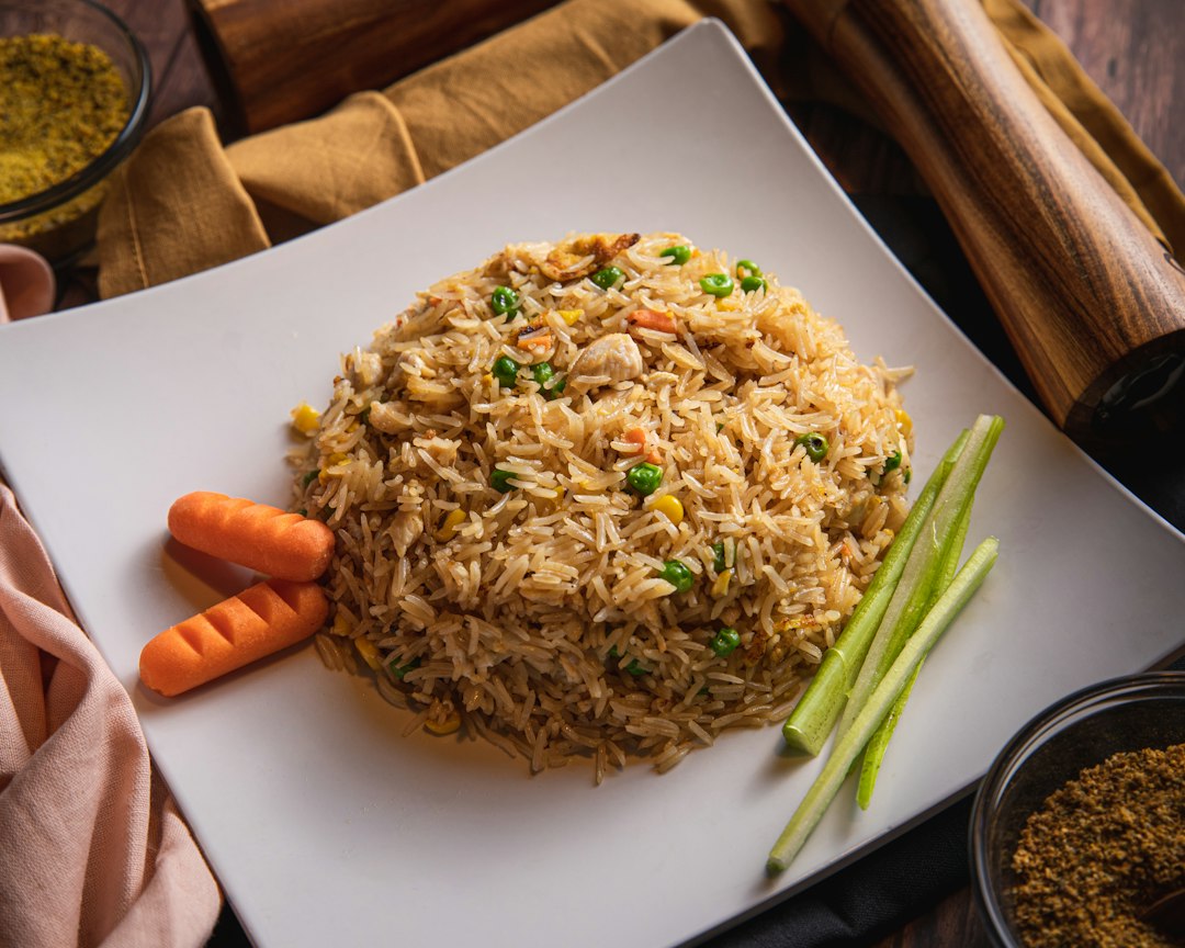 Vegetable fried rice with peas and carrots on a white square plate