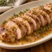 Sliced pork tenderloin with maple mustard sauce on a cream platter, finished with whole-grain mustard and fresh thyme