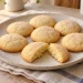 Small batch egg yolk sugar cookies with oil on an ivory plate, with one cookie broken open